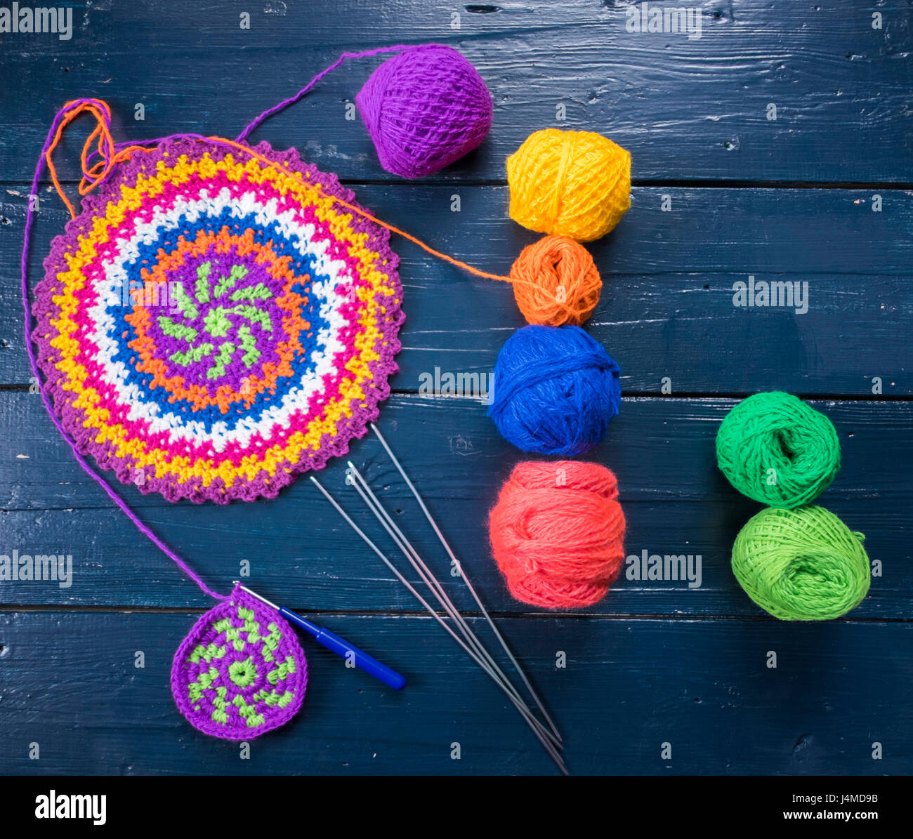 Knitting needles and multicolor yarn on blue table Stock Photo