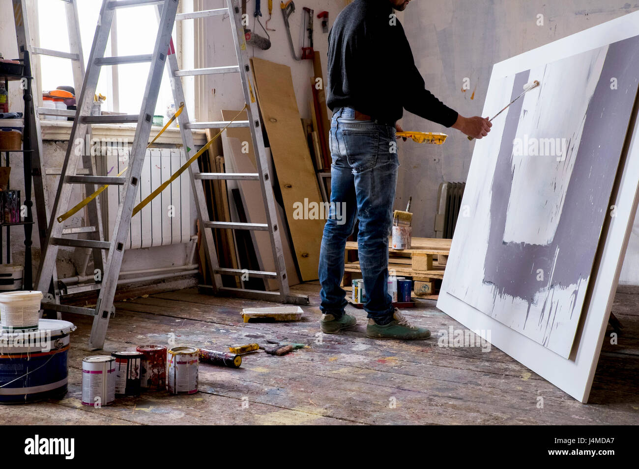 Caucasian artist painting with paint roller Stock Photo