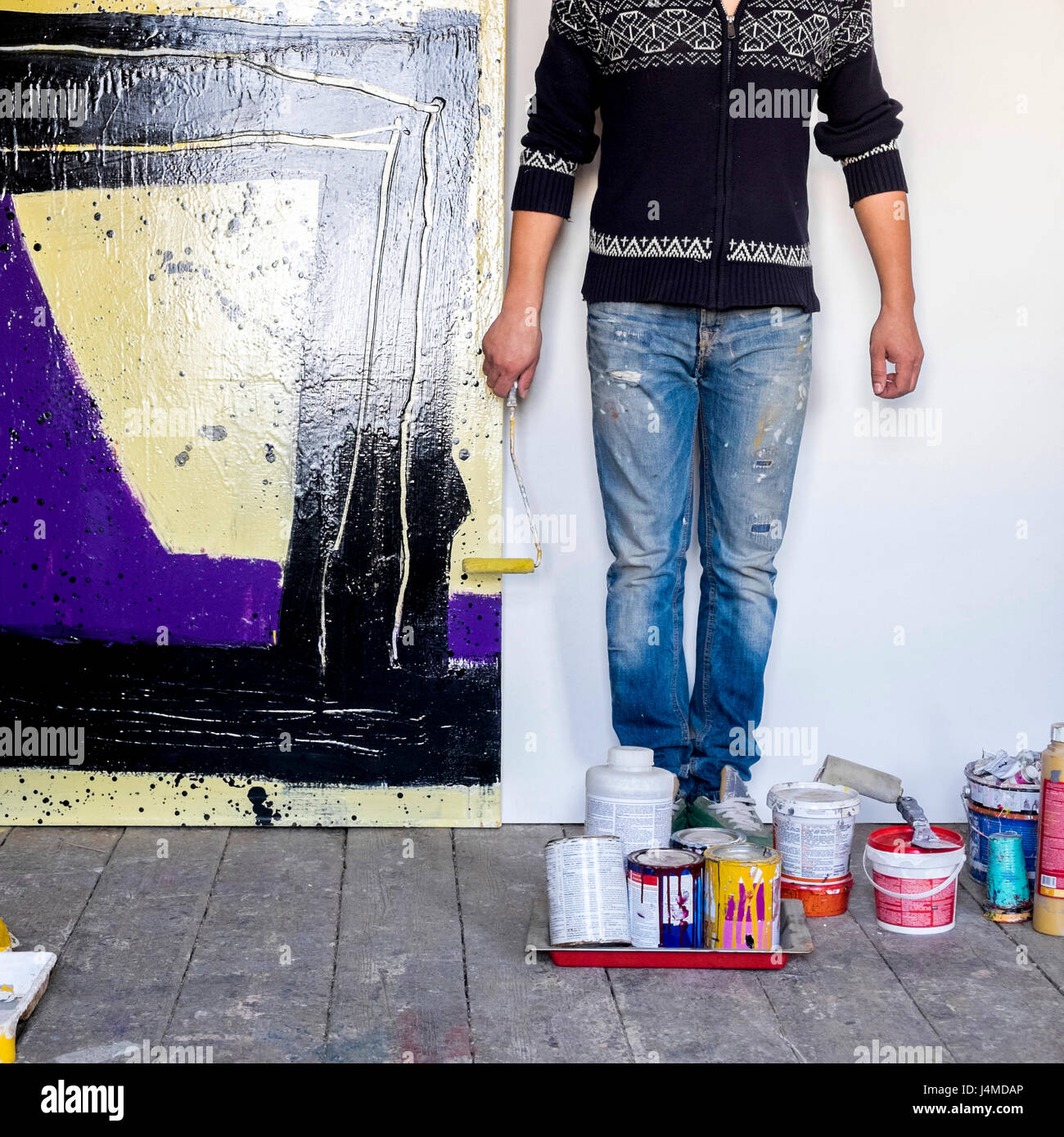 Caucasian artist holding paint roller near painting Stock Photo