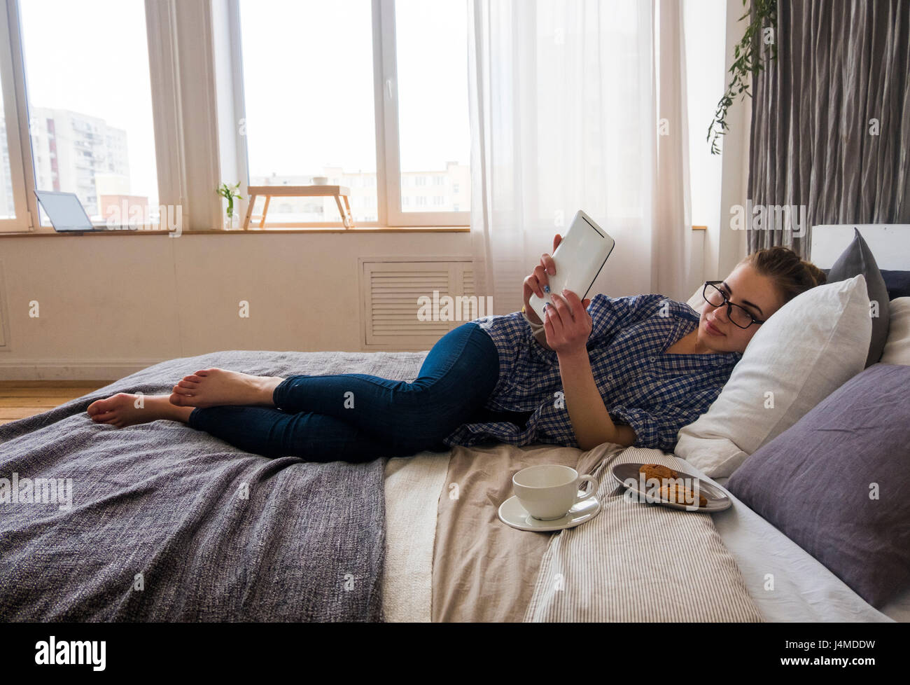 Caucasian woman laying on bed reading digital tablet Stock Photo