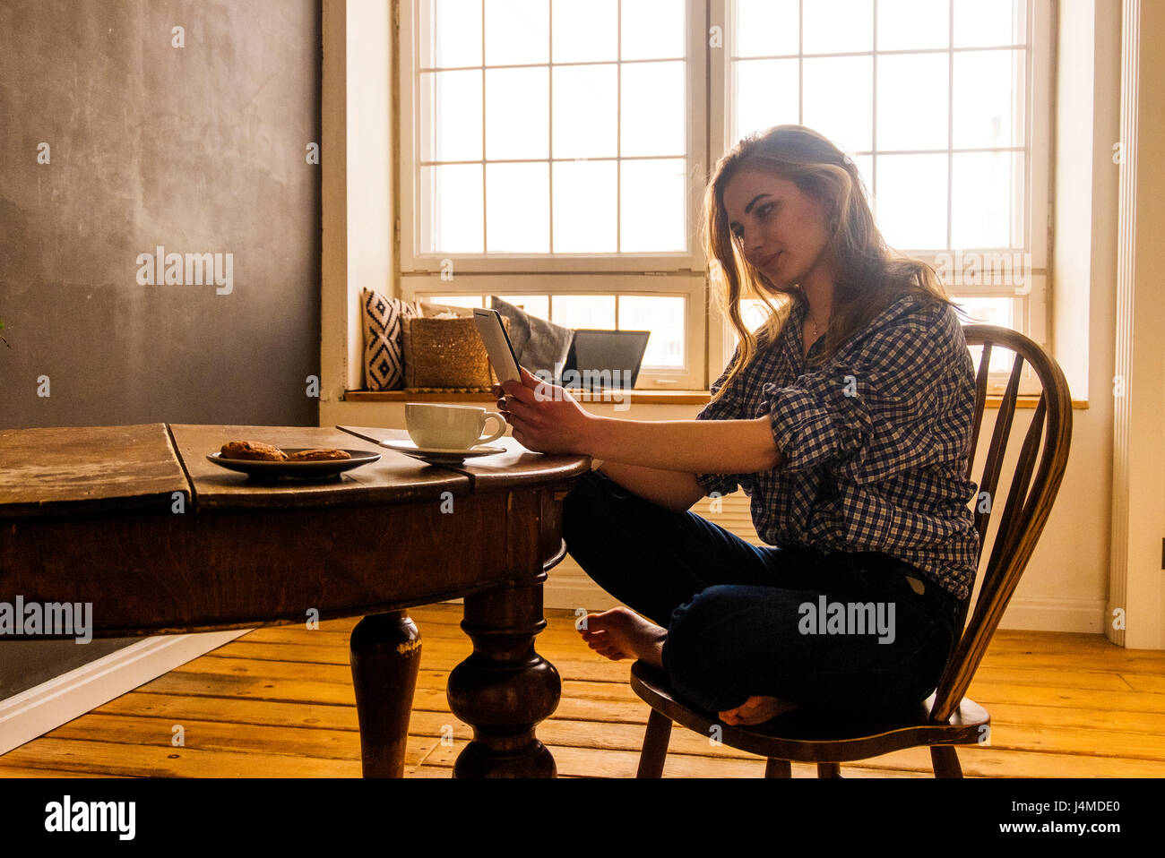 Caucasian woman reading digital tablet at table Stock Photo