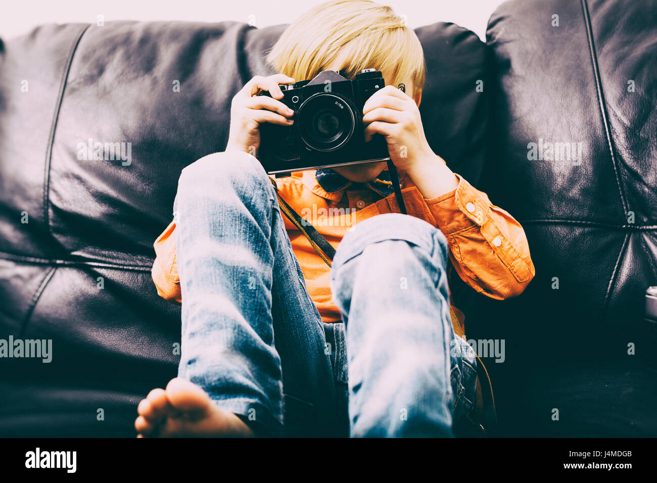 Caucasian boy sitting on sofa using camera Stock Photo