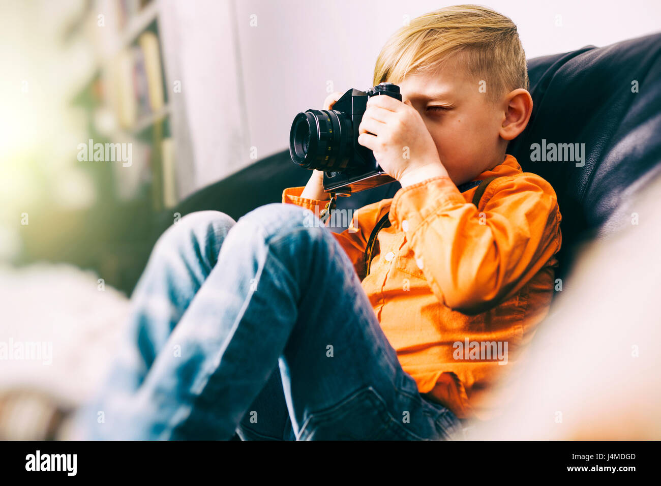 Caucasian boy sitting on sofa using camera Stock Photo