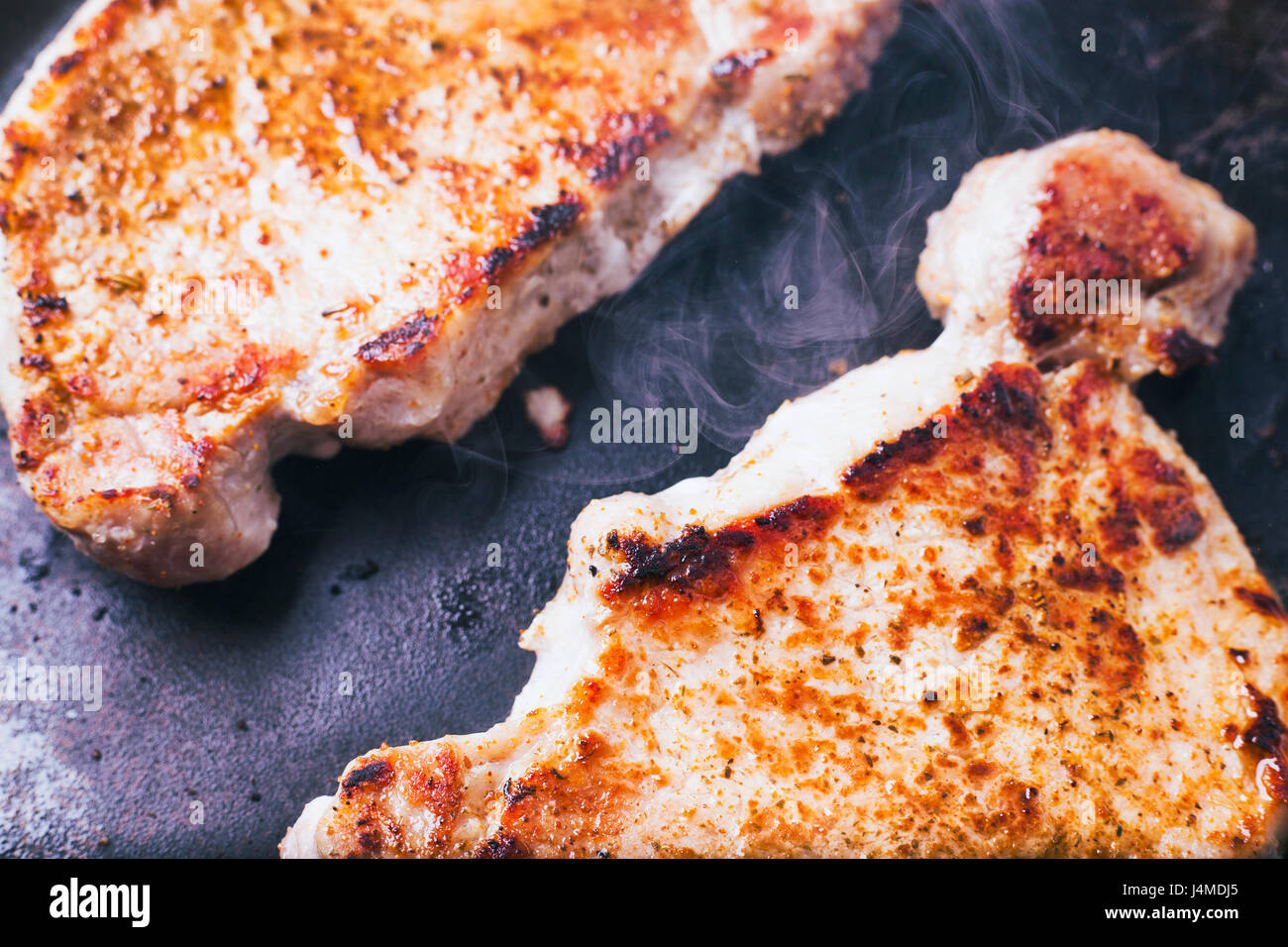 Pork chops searing in pan Stock Photo