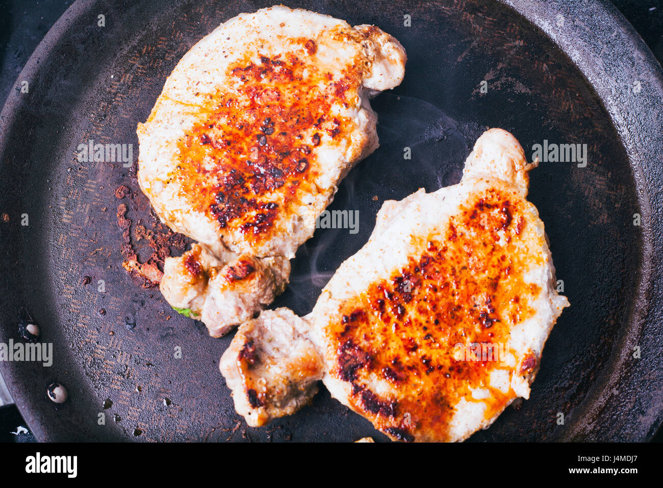 Pork chops searing in pan Stock Photo