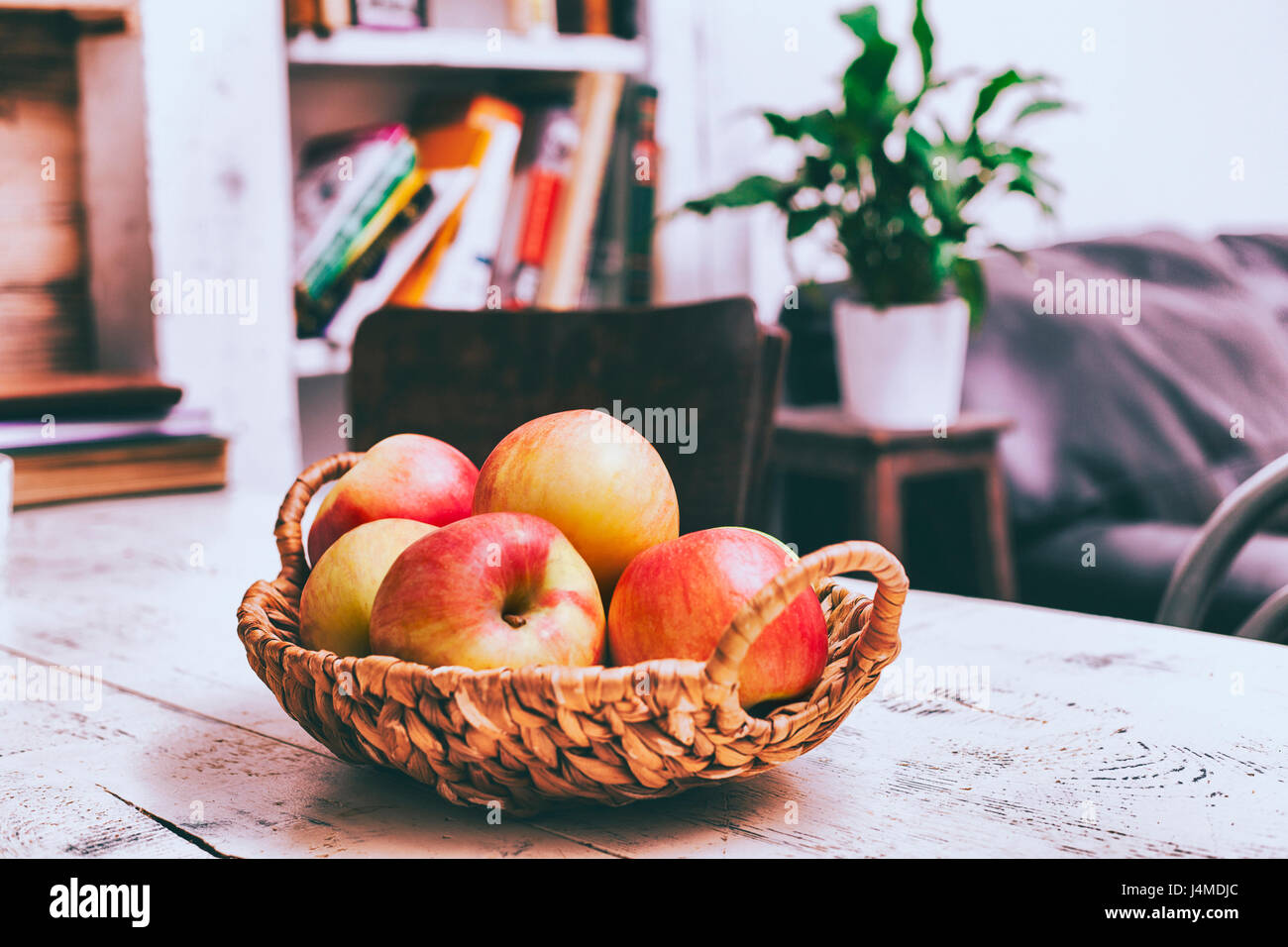 Basket of apples on wooden table in livingroom Stock Photo