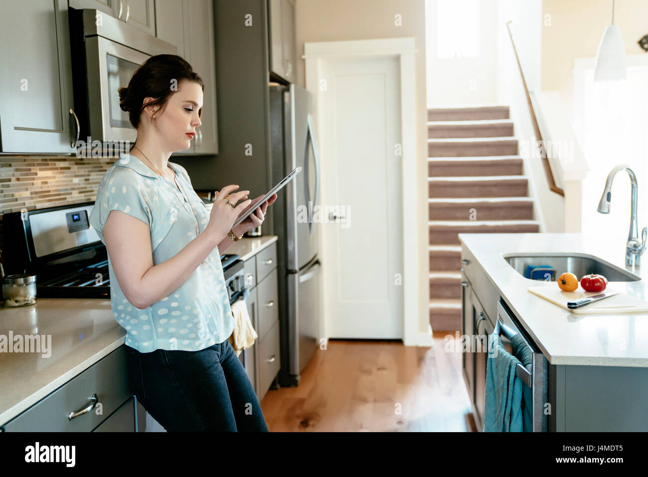 Woman using digital tablet in domestic kitchen Stock Photo