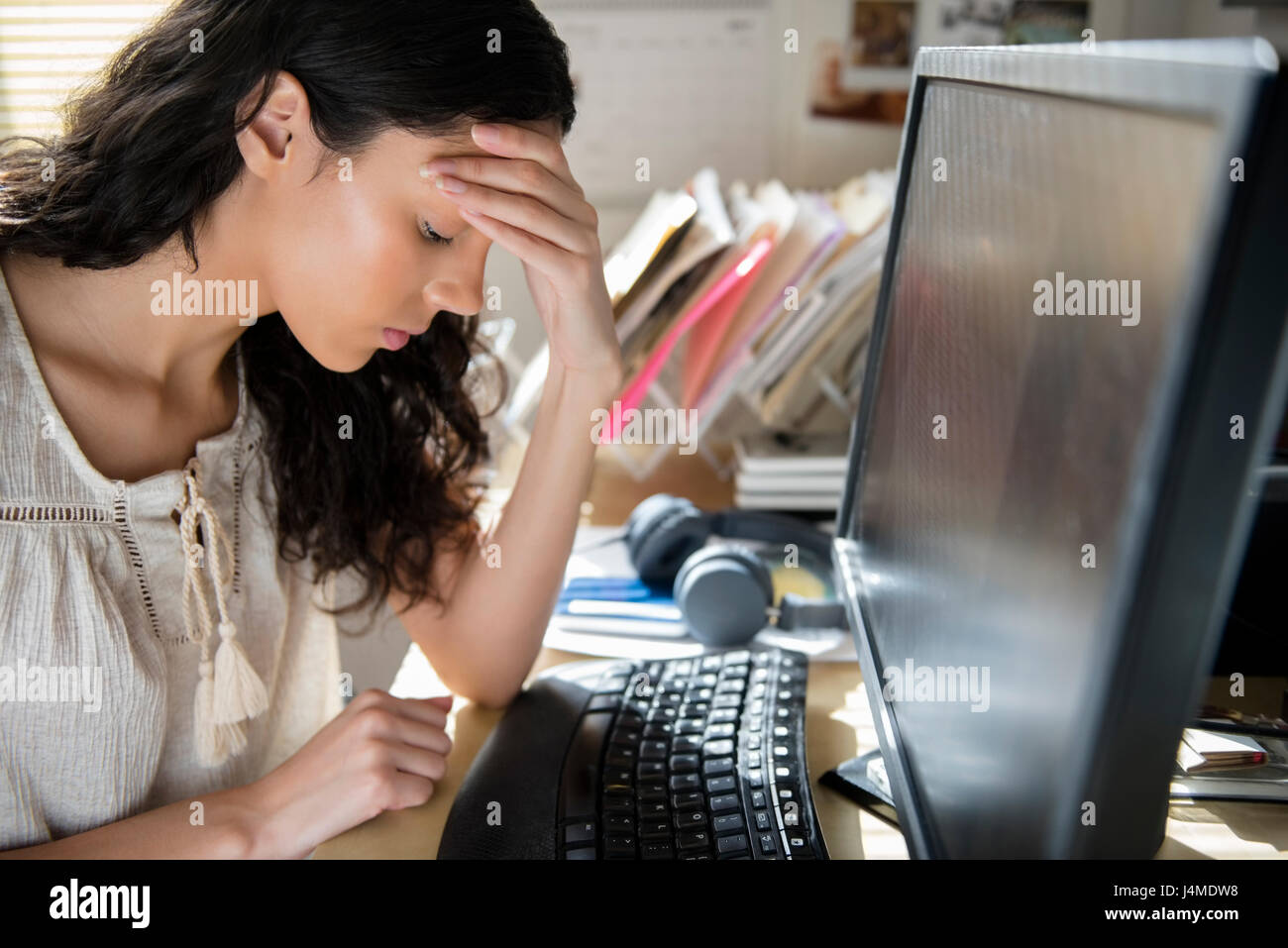 Frustrated Hispanic woman using computer Stock Photo