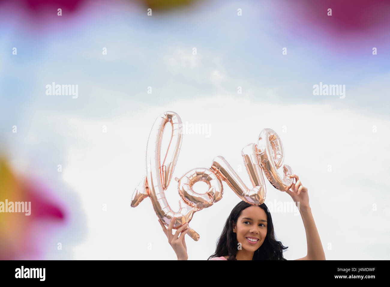Hispanic woman holding love balloon outdoors Stock Photo