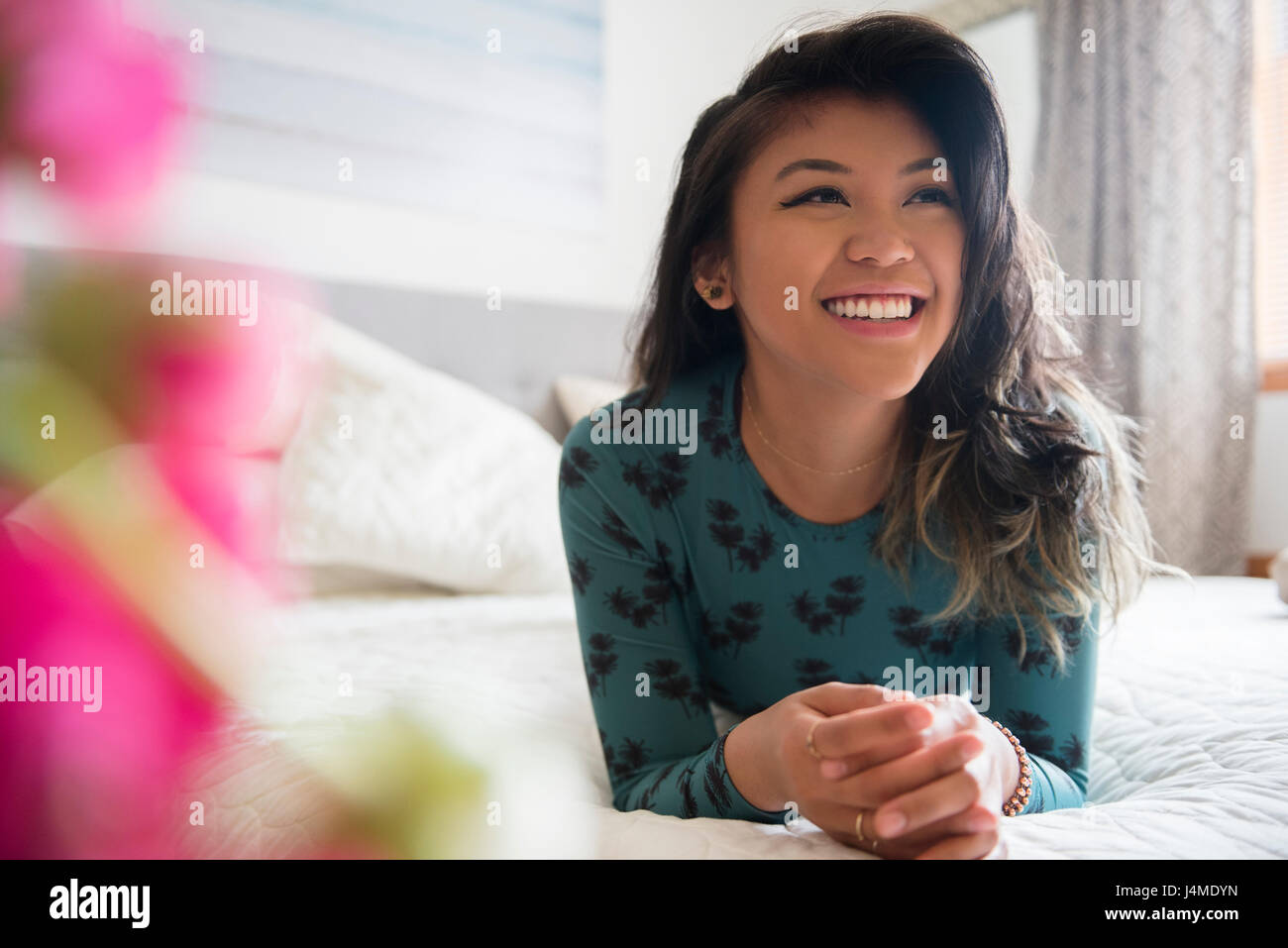 Smiling Mixed Race woman laying on bed Stock Photo