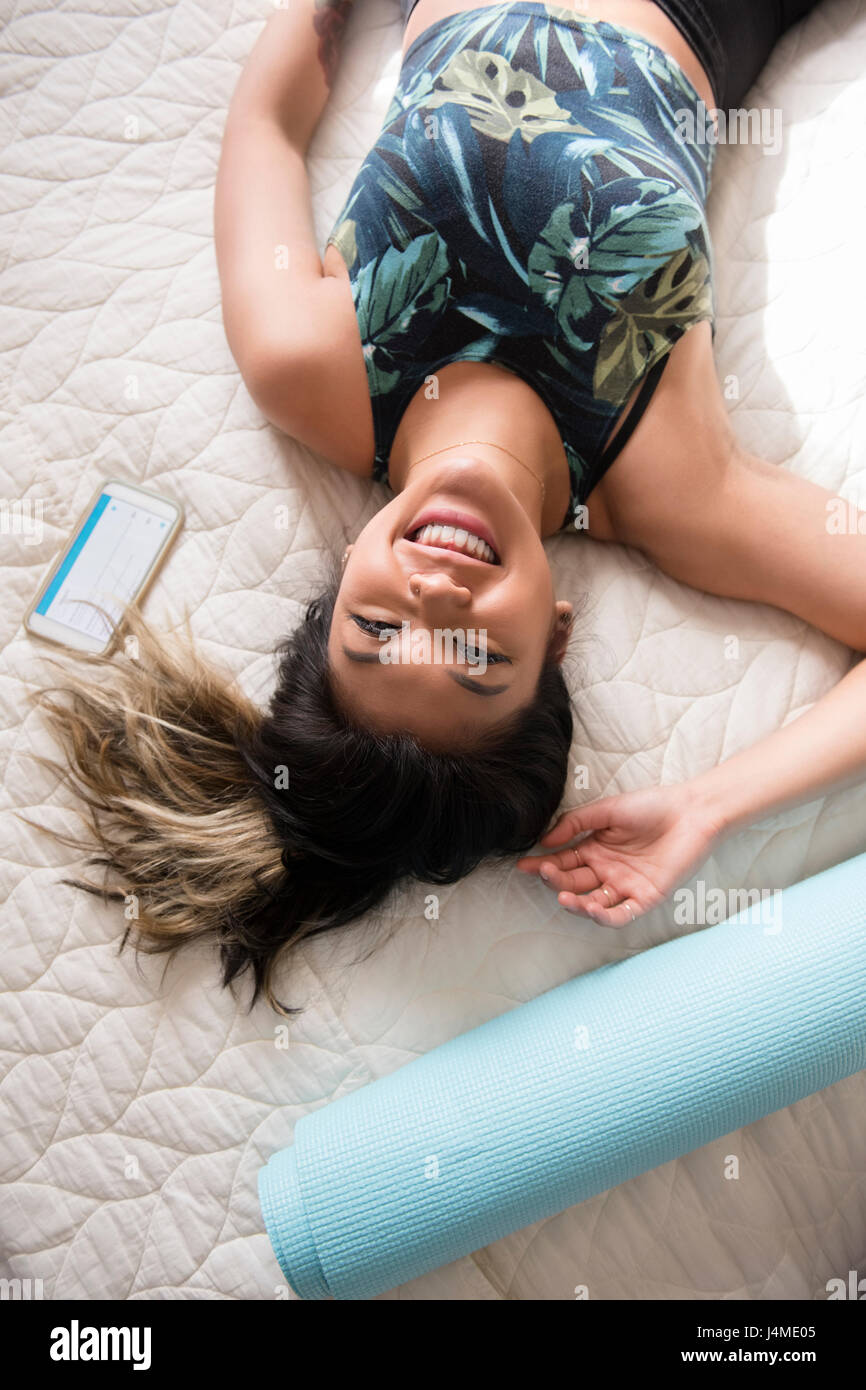 Smiling Mixed Race woman laying on bed resting after workout Stock Photo