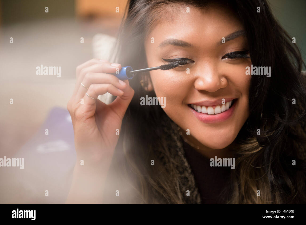 Mixed Race woman applying mascara Stock Photo