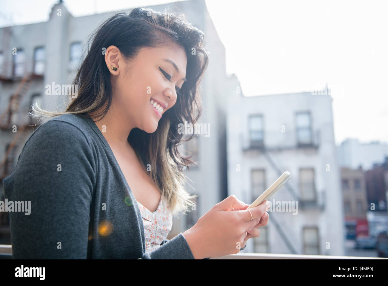 Mixed Race woman texting on cell phone in city Stock Photo