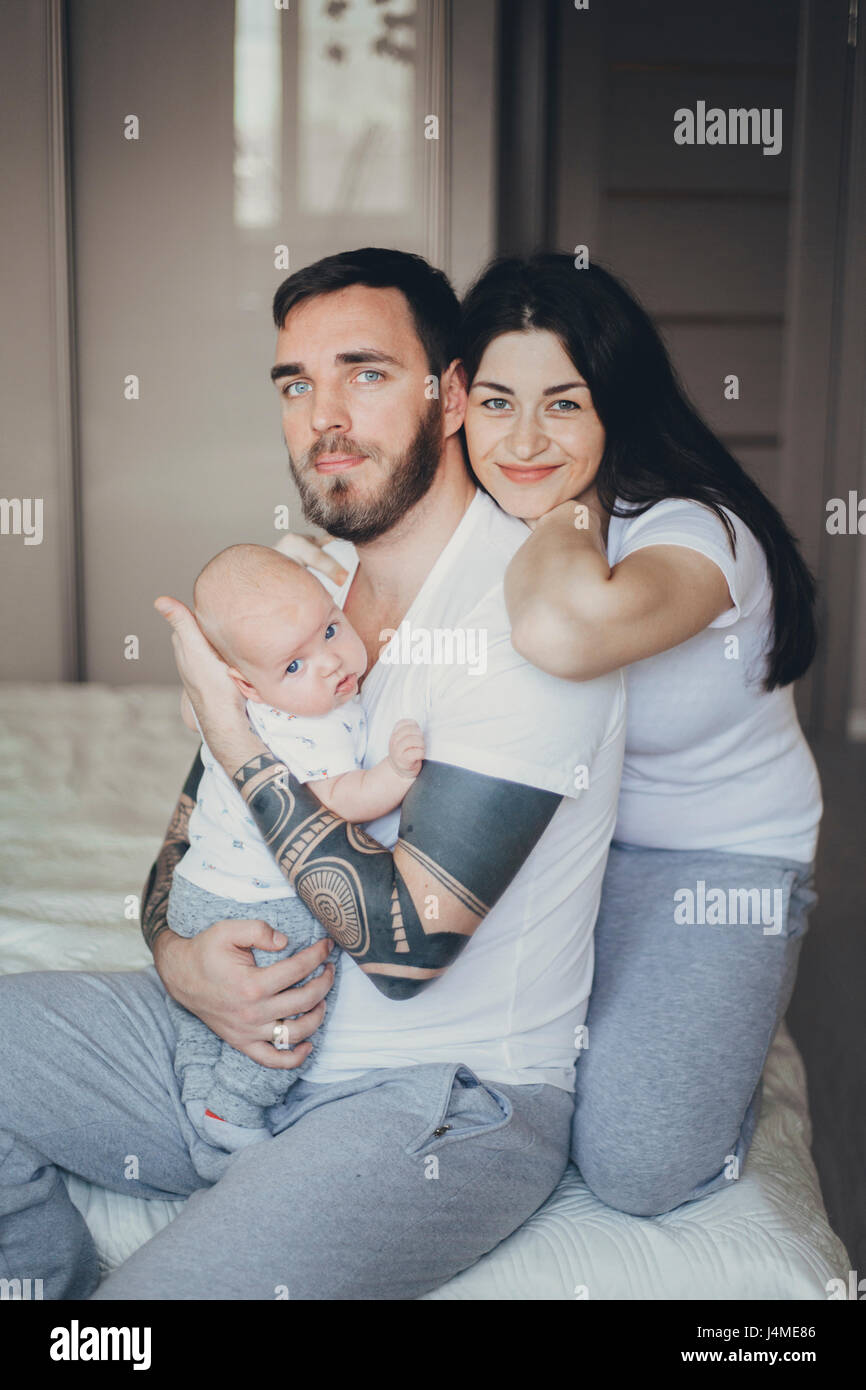 Portrait of Caucasian mother and father on bed with baby son Stock Photo