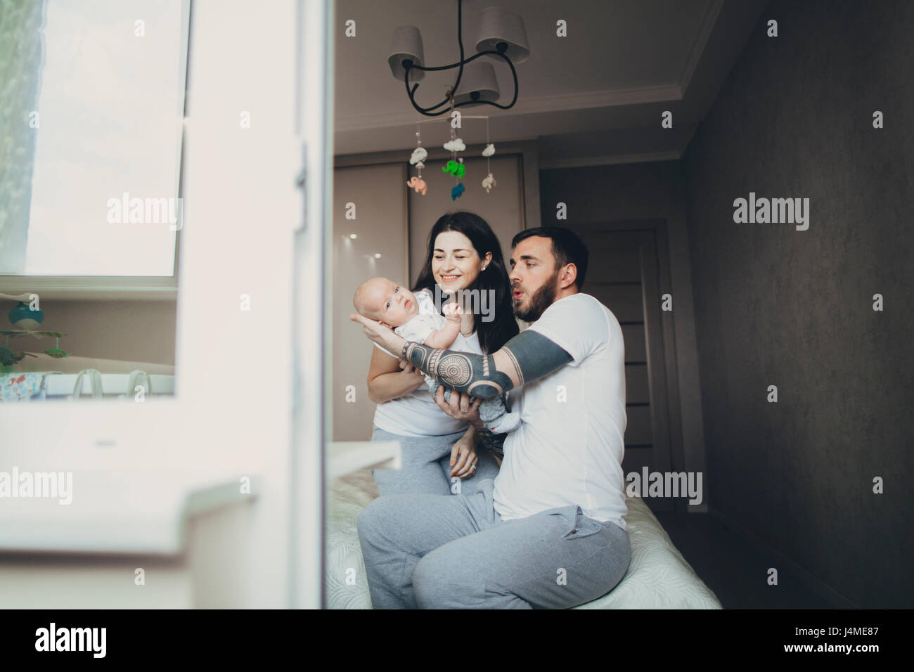 Caucasian mother and father on bed playing with baby son Stock Photo