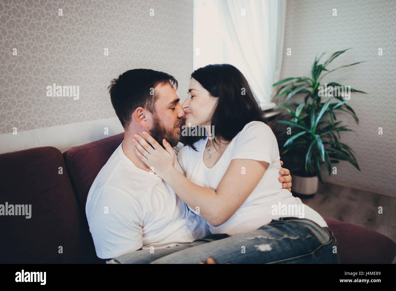 Caucasian couple cuddling and kissing on sofa Stock Photo