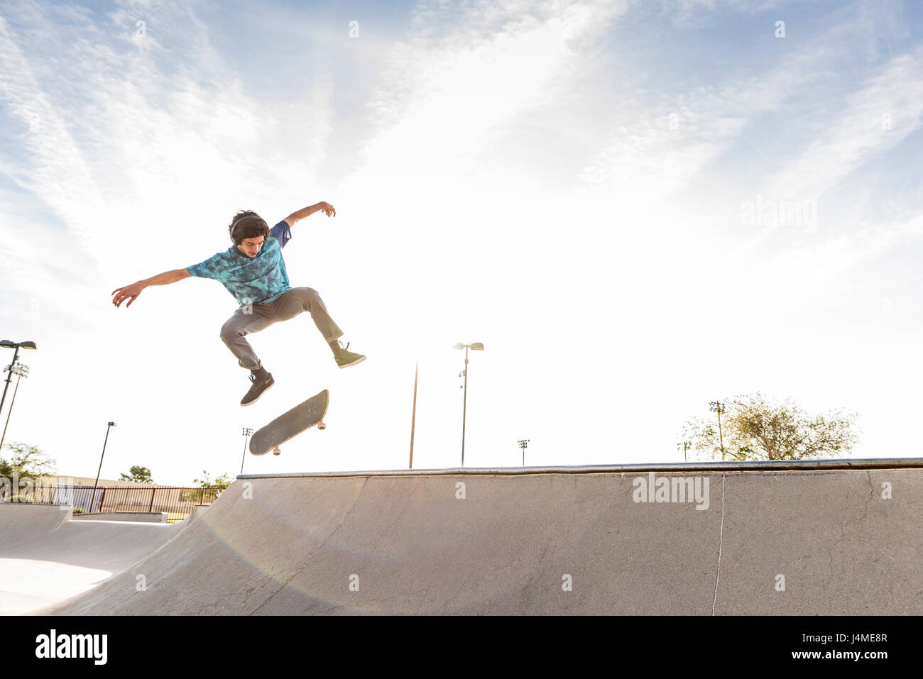 Hispanic man performing mid-air trick on skateboard Stock Photo