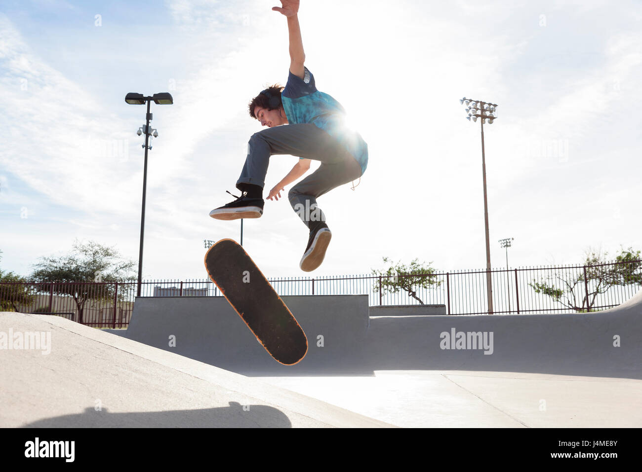 Hispanic man performing mid-air trick on skateboard Stock Photo