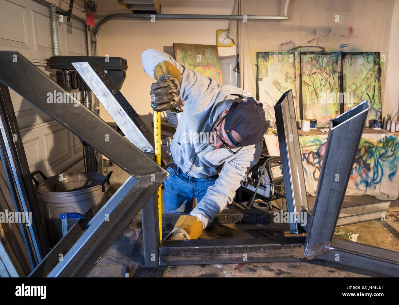 Caucasian man measuring metal sculpture with tape measure Stock Photo