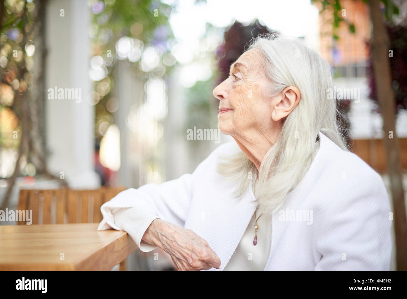 Profile of smiling older Caucasian woman sitting at table Stock Photo