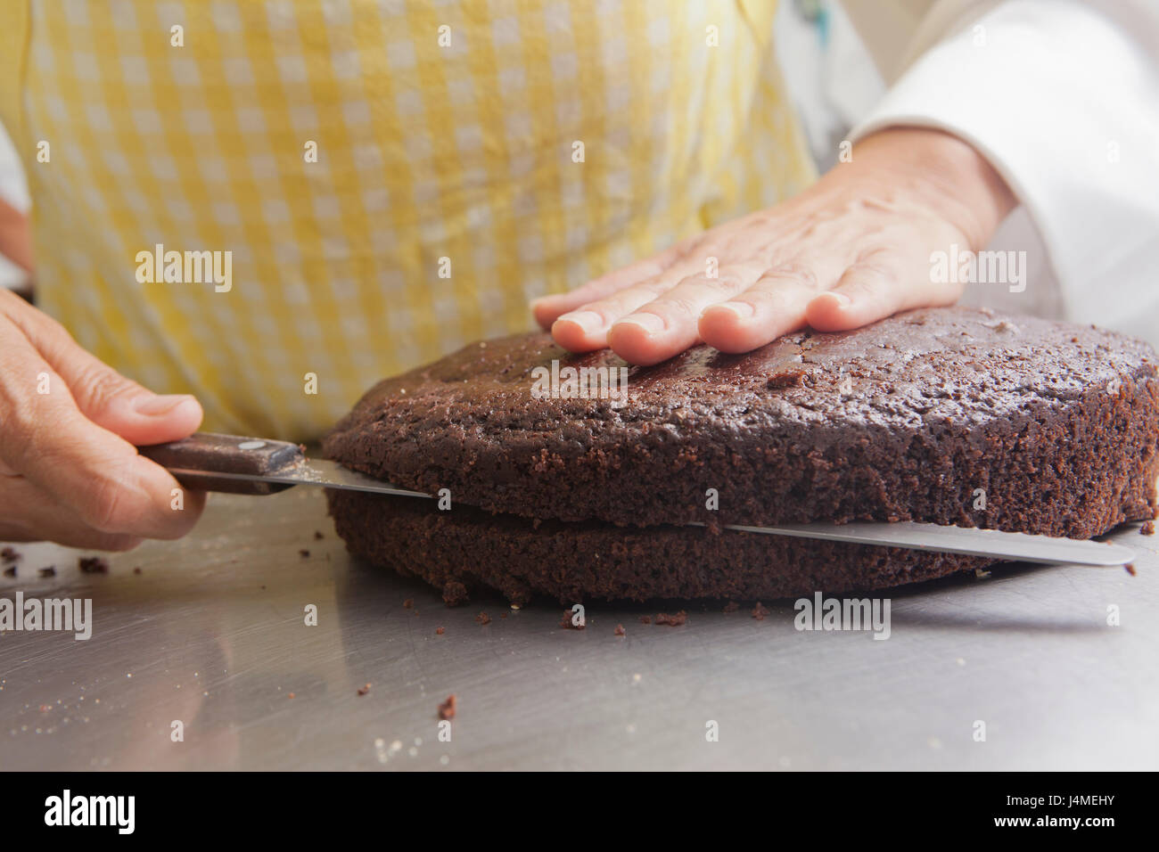 Hispanic woman cutting cake with knife Stock Photo