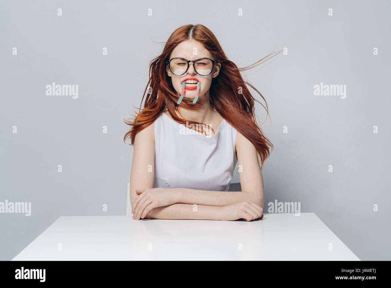 Caucasian woman sitting at windy table with candy in mouth Stock Photo ...