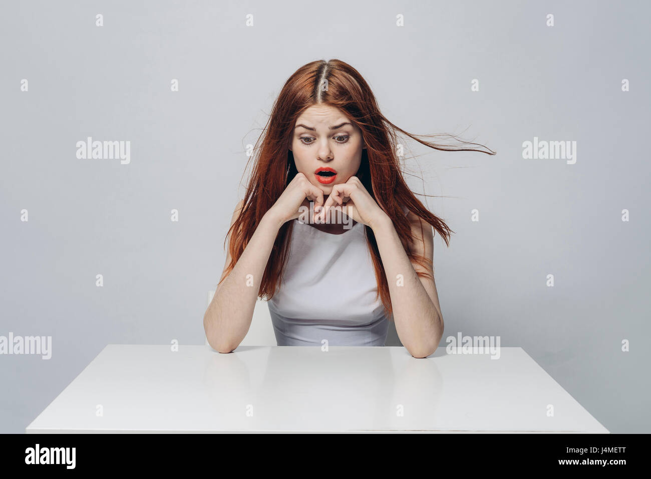 Surprised Caucasian woman sitting at windy table Stock Photo - Alamy