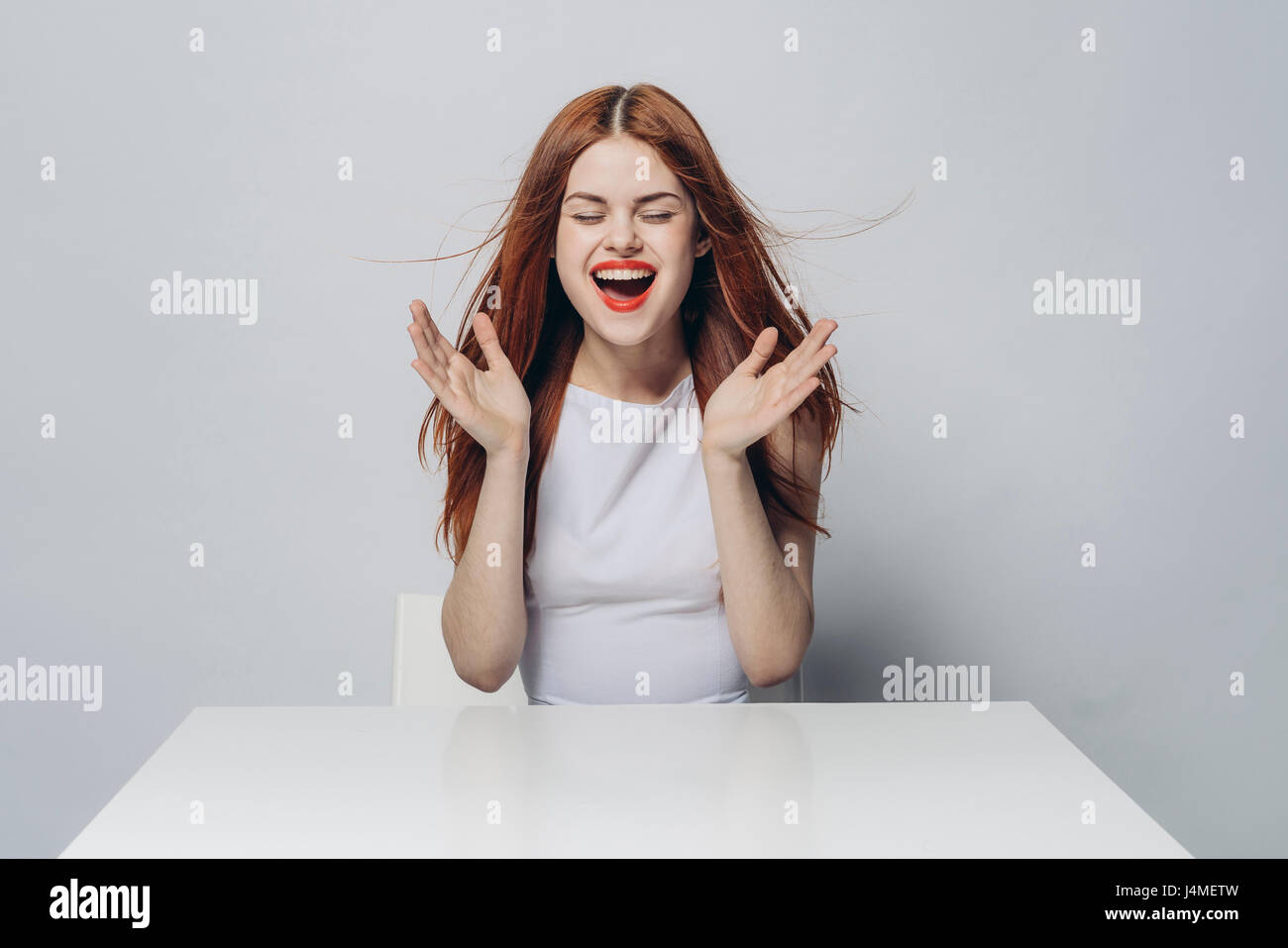 Excited Caucasian woman sitting at windy table Stock Photo