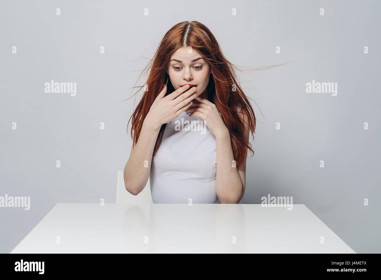 Surprised Caucasian woman sitting at windy table Stock Photo