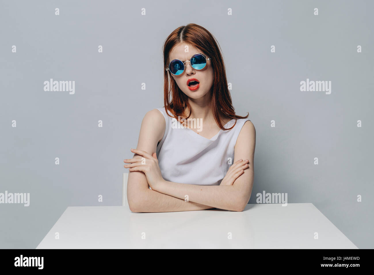 Caucasian woman with attitude sitting at table wearing sunglasses Stock Photo