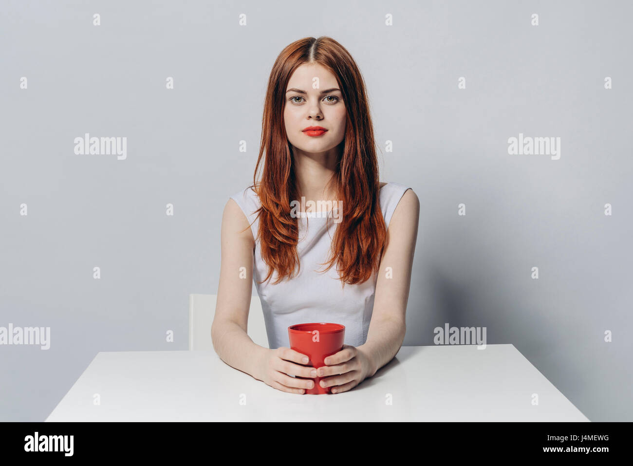 Caucasian woman sitting at table holding red cup Stock Photo