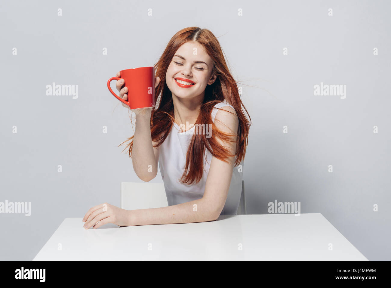 Caucasian woman sitting at windy table holding red cup Stock Photo