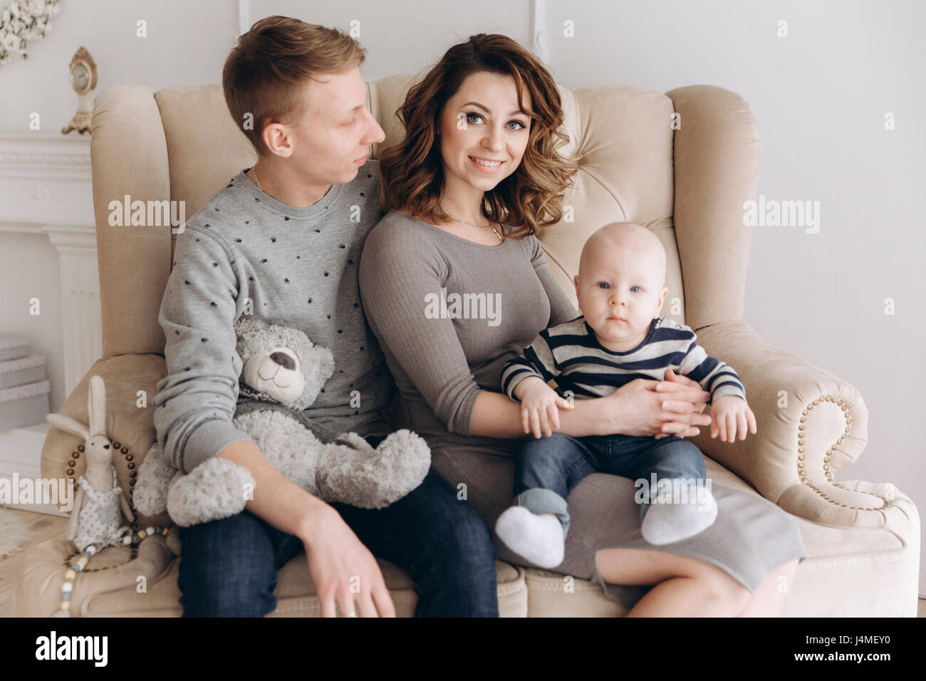 Portrait of Caucasian mother and father on love seat with baby son Stock Photo