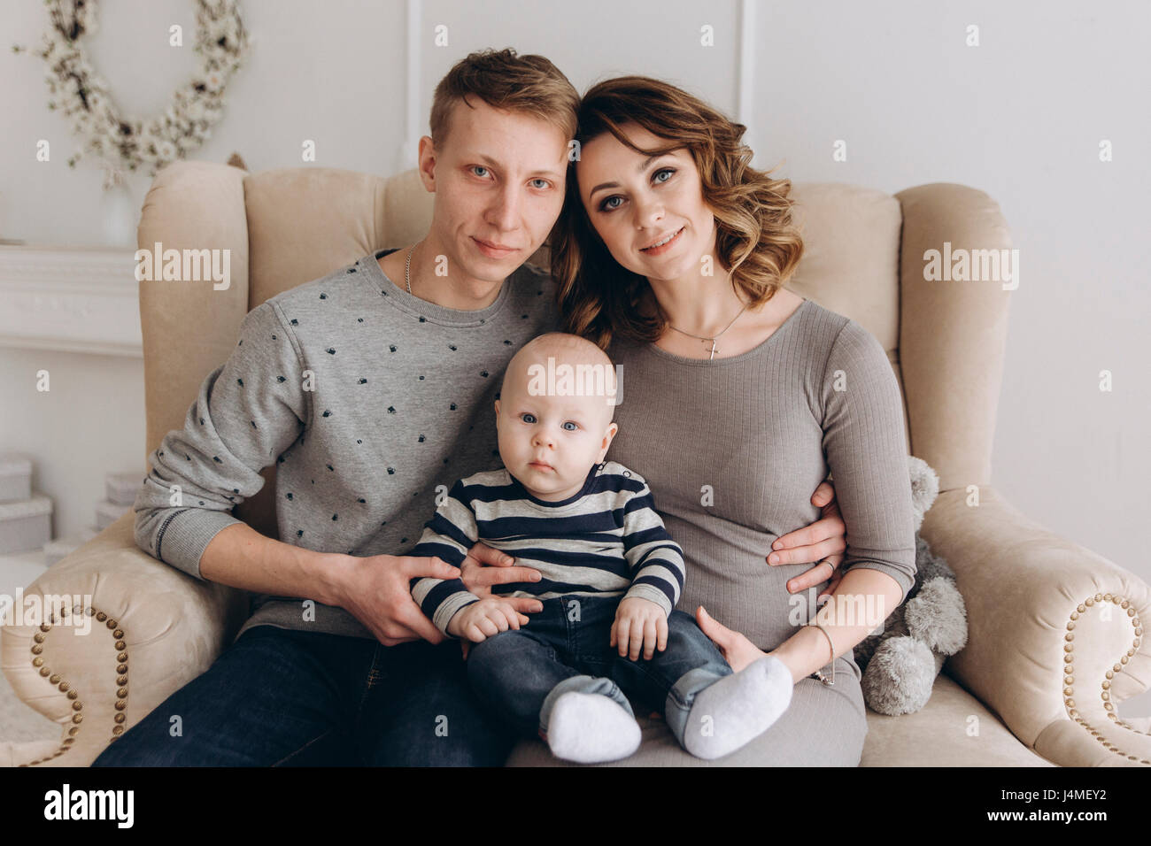 Portrait of Caucasian mother and father on love seat with baby son Stock Photo