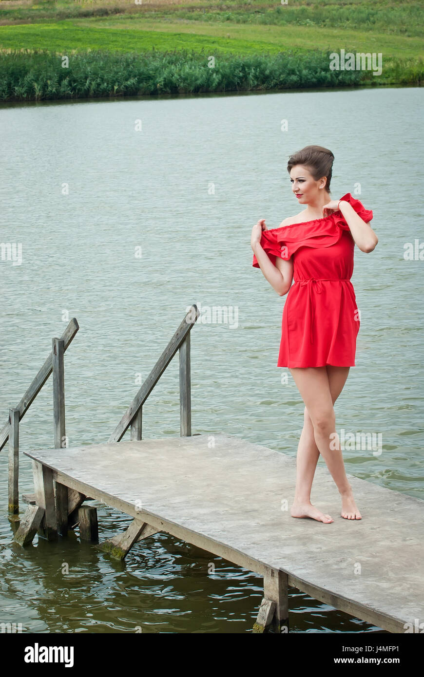 Girl on the pier at the lake in summer in red dress Stock Photo - Alamy