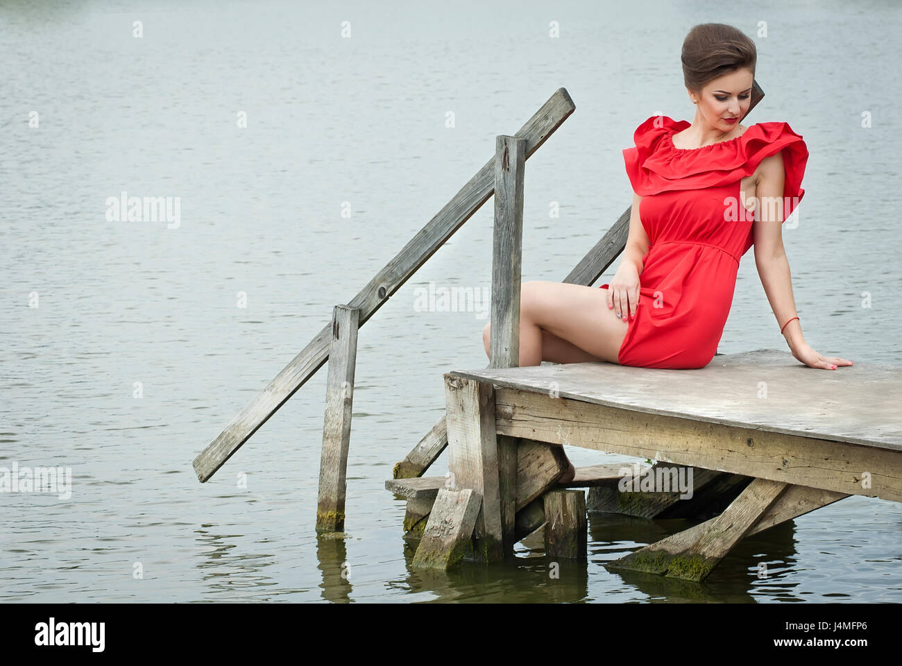 Girl on the pier at the lake in summer in red dress Stock Photo - Alamy