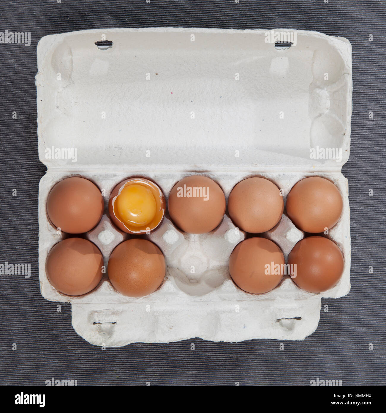 A broken egg among whole eggs in an egg carton Stock Photo Alamy