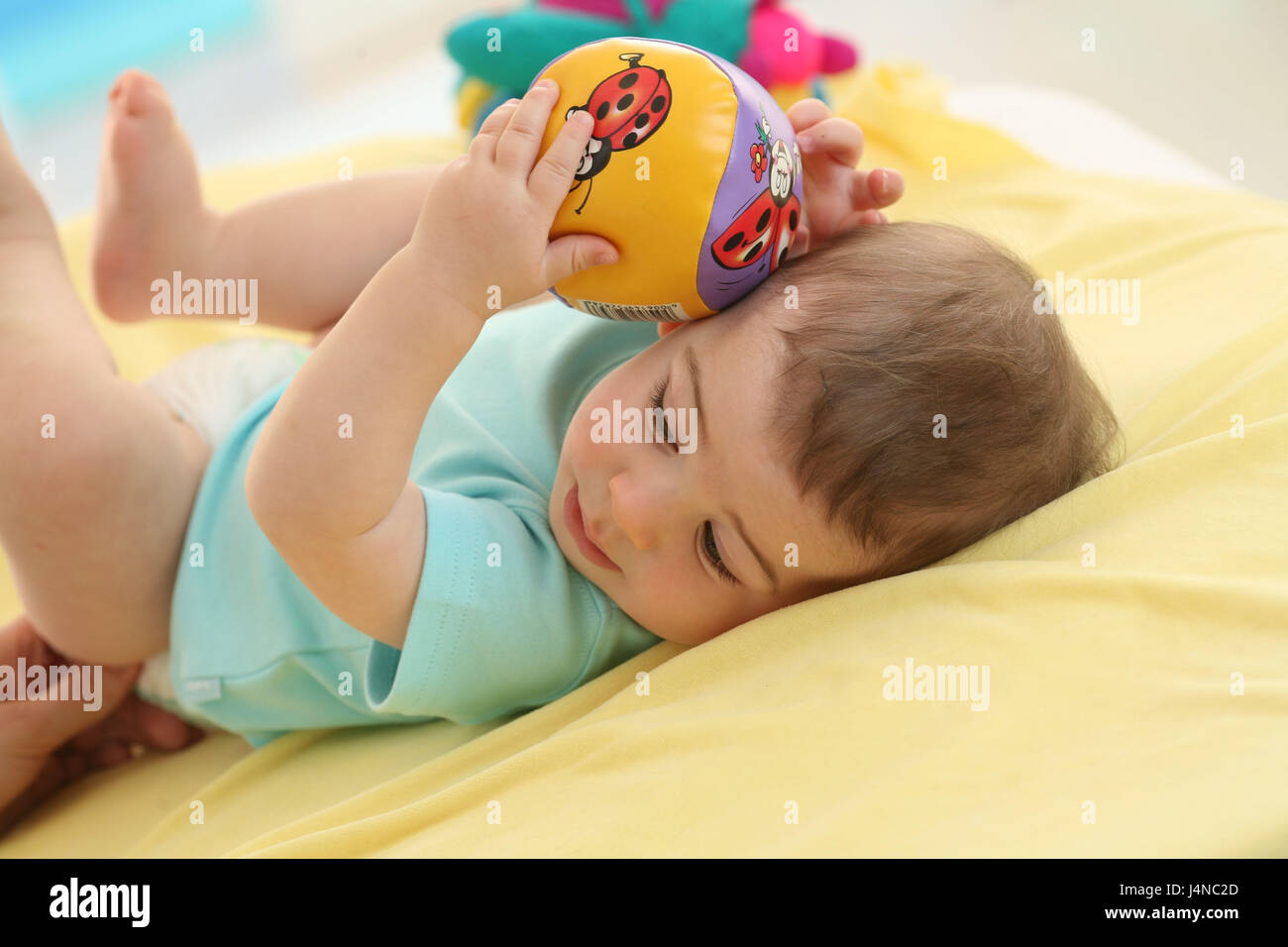 Baby, 7 months, lie, hold ball, at the side, Stock Photo
