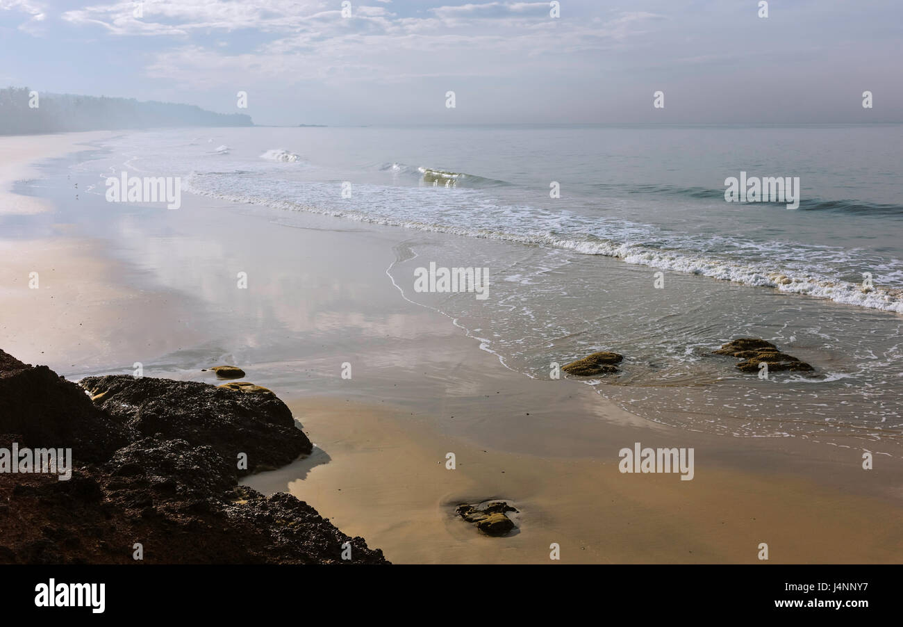 Dawn mist lifts over the beautiful sandy beach at low tide with the Arabian Sea on a fine winter morning near Thottada village, Kannur, Kerala, India. Stock Photo