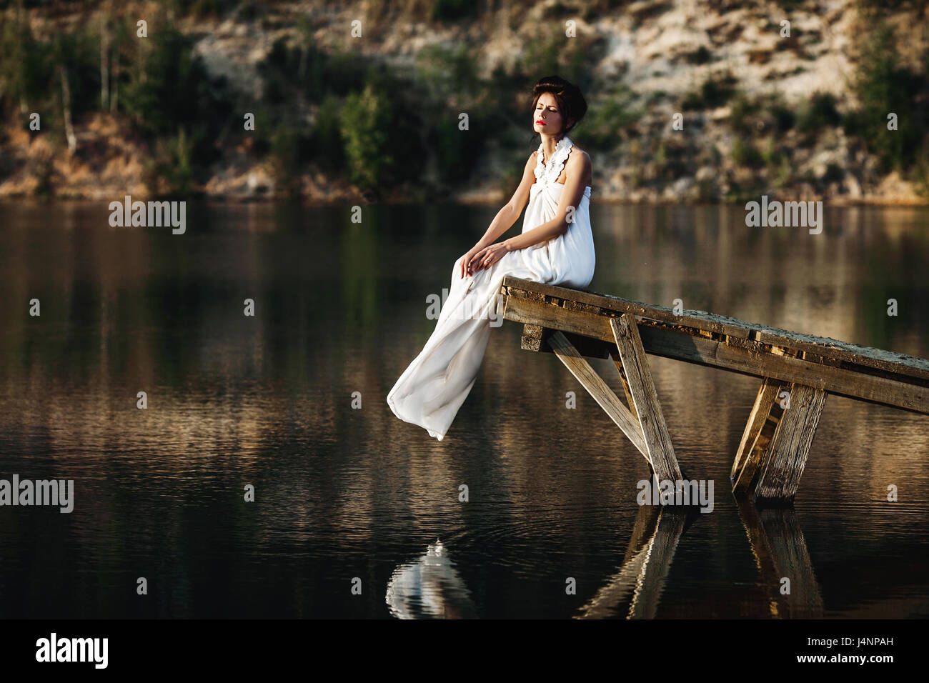 girl sitting on a wooden pier on a river or a lake Stock Photo - Alamy
