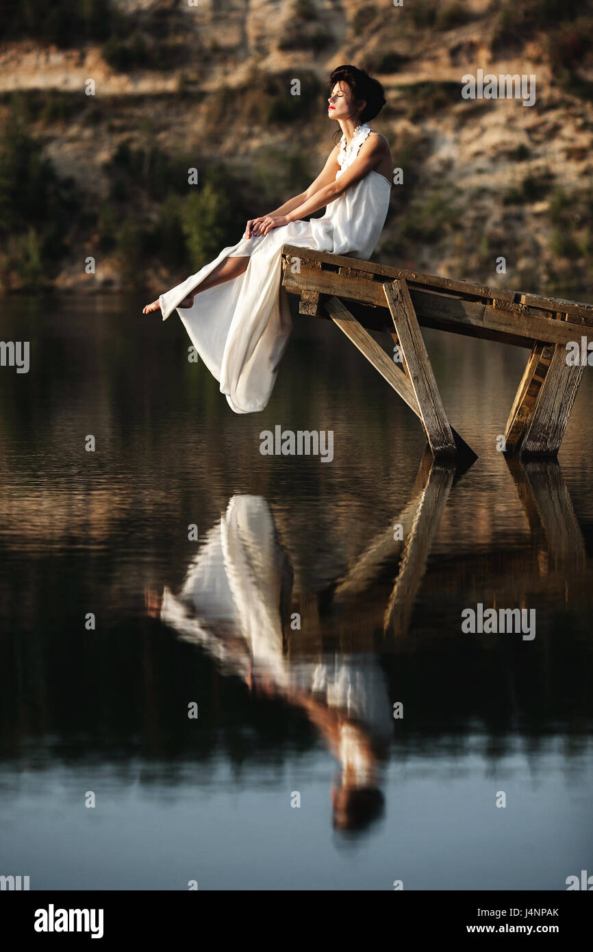 girl sitting on a wooden pier on a river or a lake Stock Photo - Alamy