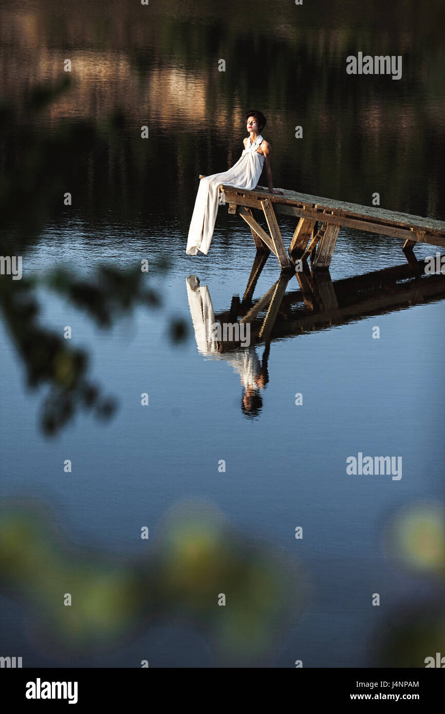 girl sitting on a wooden pier on a river or a lake Stock Photo - Alamy