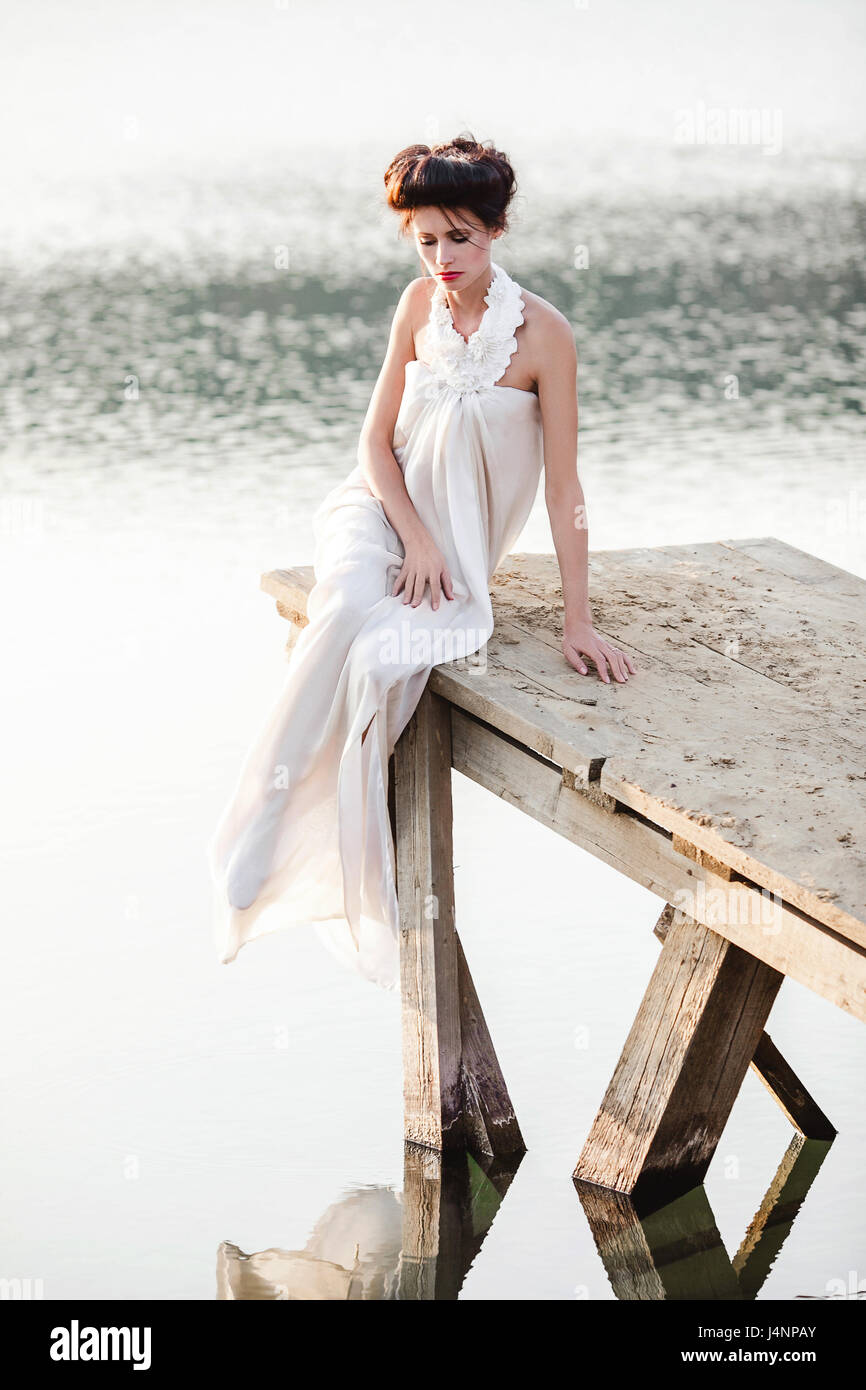 girl in white dress sitting on a wooden pier Stock Photo - Alamy