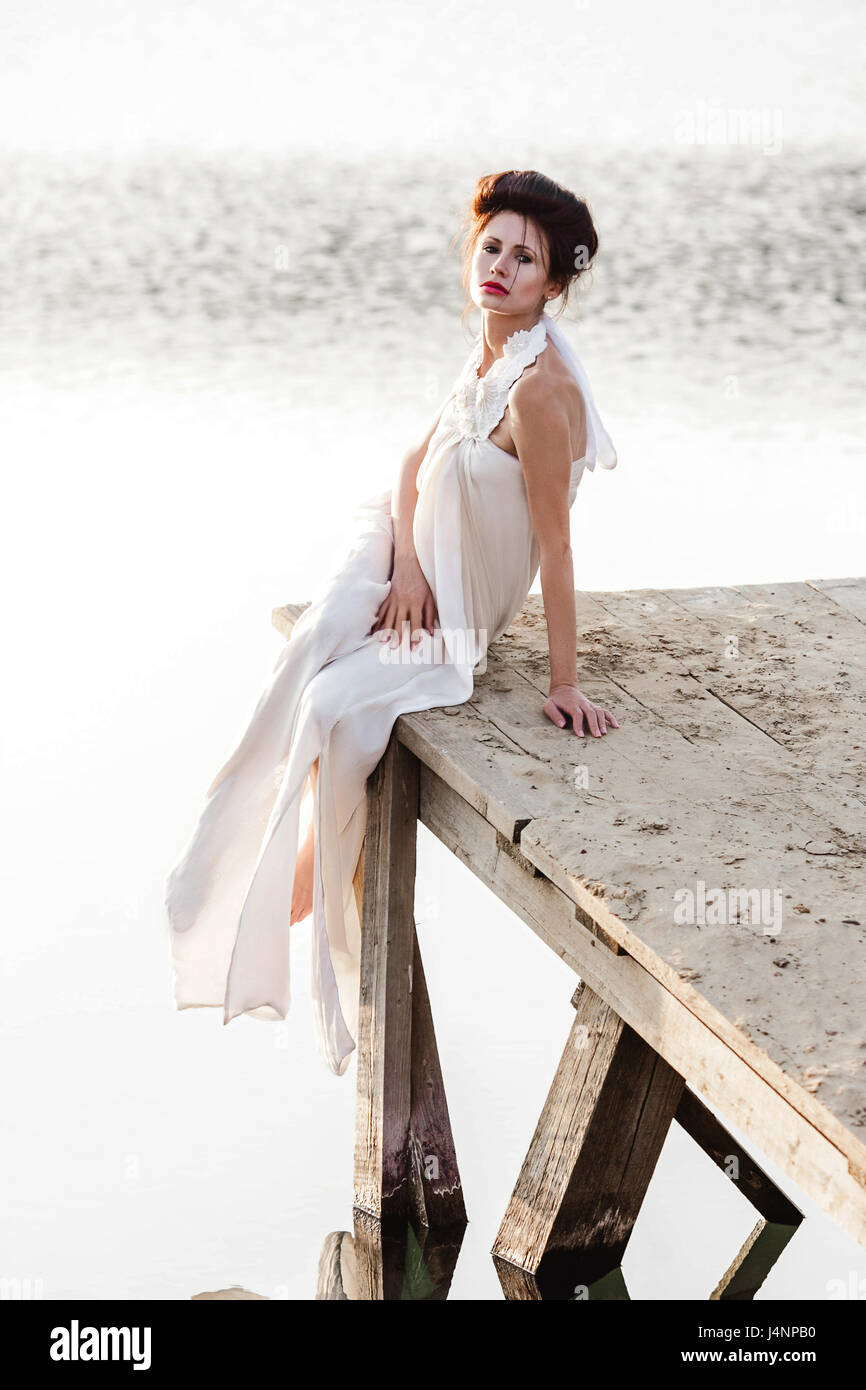 girl in white dress sitting on a wooden pier Stock Photo - Alamy