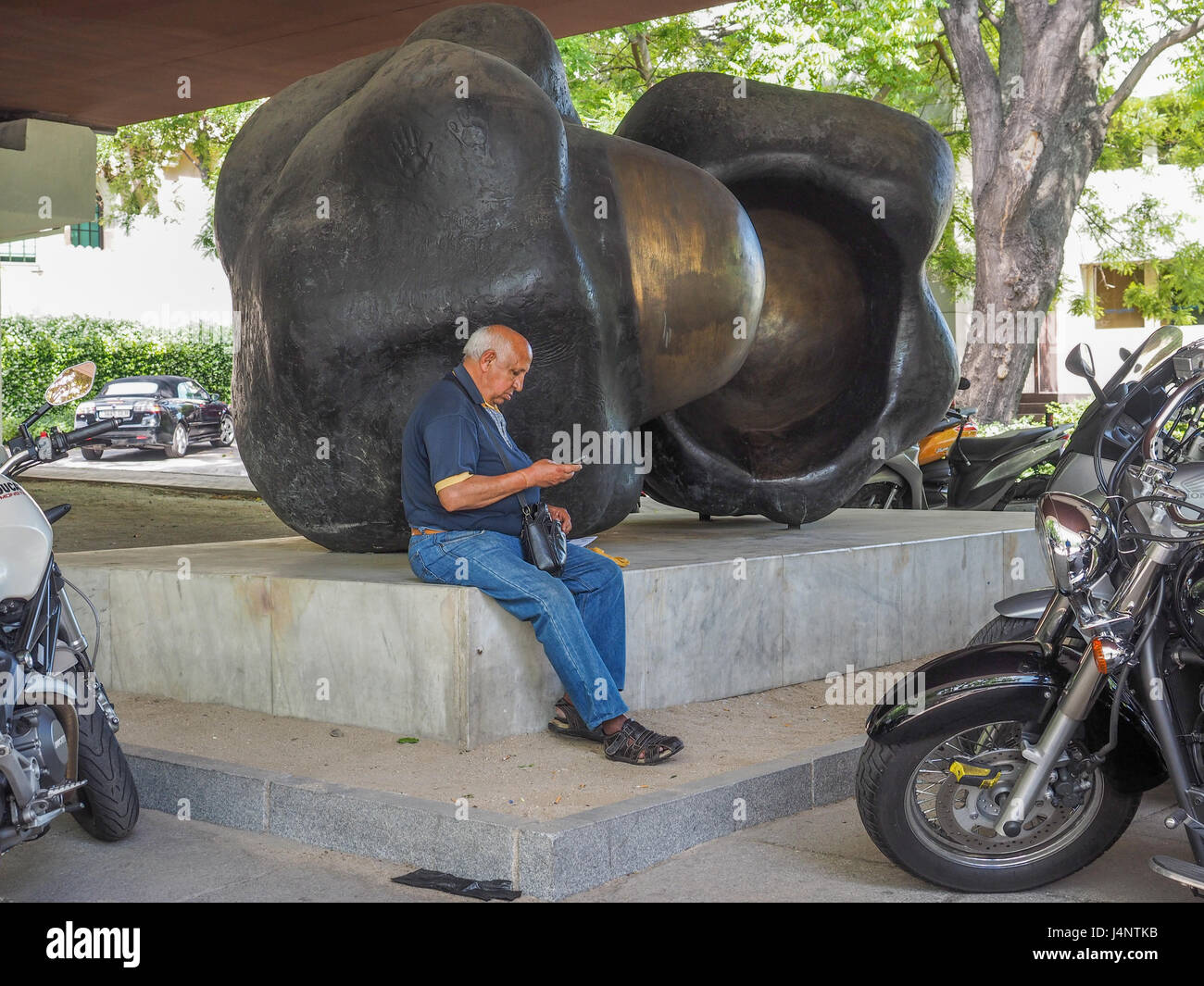 a view of Unidades sculpture by Pablo Serrano in the open air garden park museum Museo de escultura al aire libre Madrid man person sitting looking Stock Photo