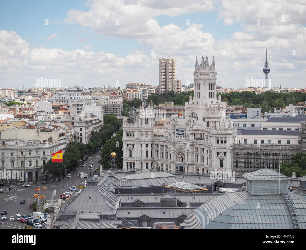 a view from above of a banner flying from Madrid city Hall council building stating that refugees welcome, Spanish flag flying, Spainroof Stock Photo