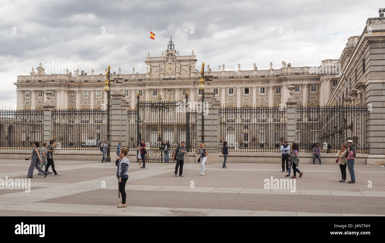 a view Madrid palace Palacio Real from the Plaza de Almeria with Spanish flag flying tourists standing walking milling in pedestrian zone Stock Photo
