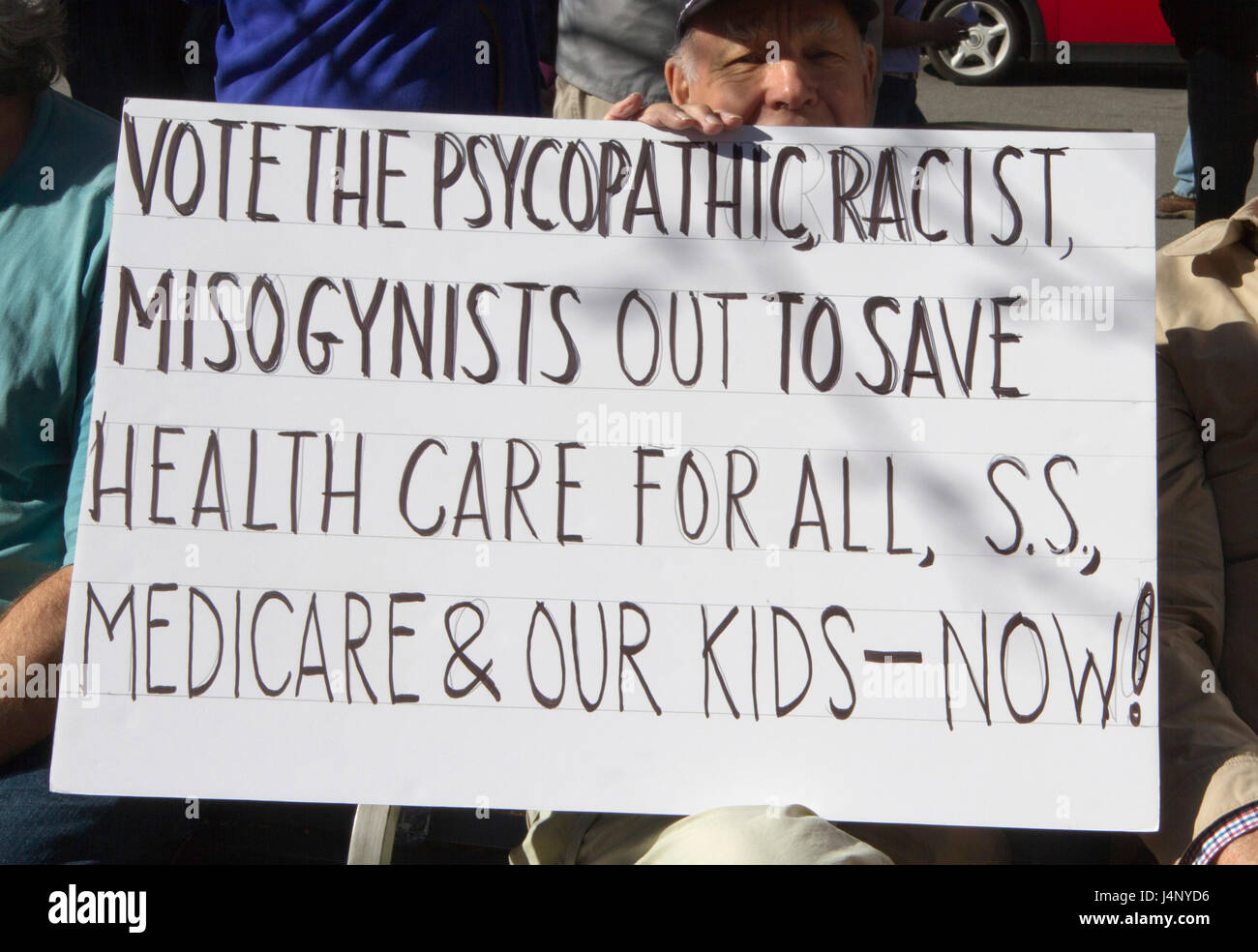 Asheville, North Carolina, USA - February 25, 2017: Older white man holds a sign saying 'Vote the Psychopathic, Racist, Misogynists Out to Save Health Stock Photo