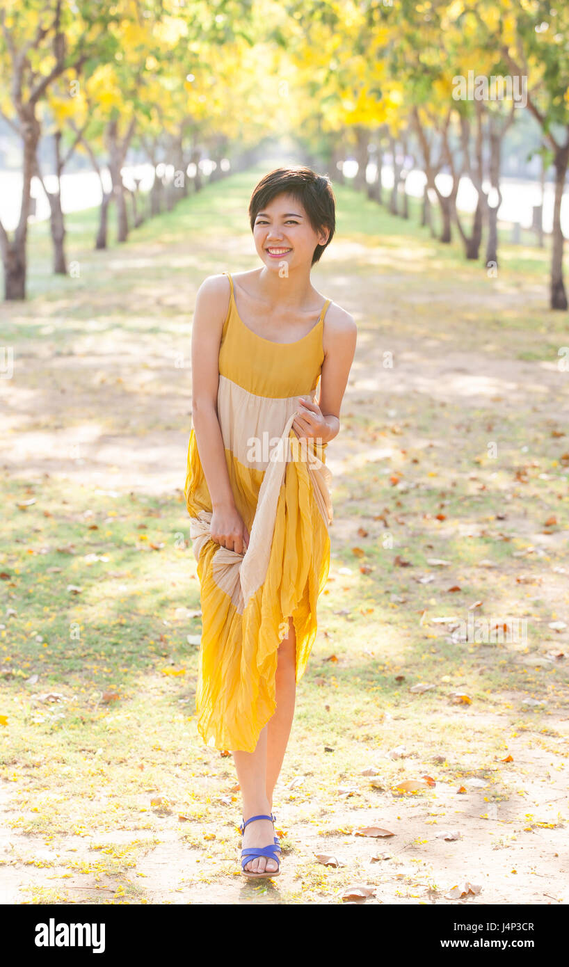 portrait of young beautiful asian woman wearing yellow dress relaxing ...