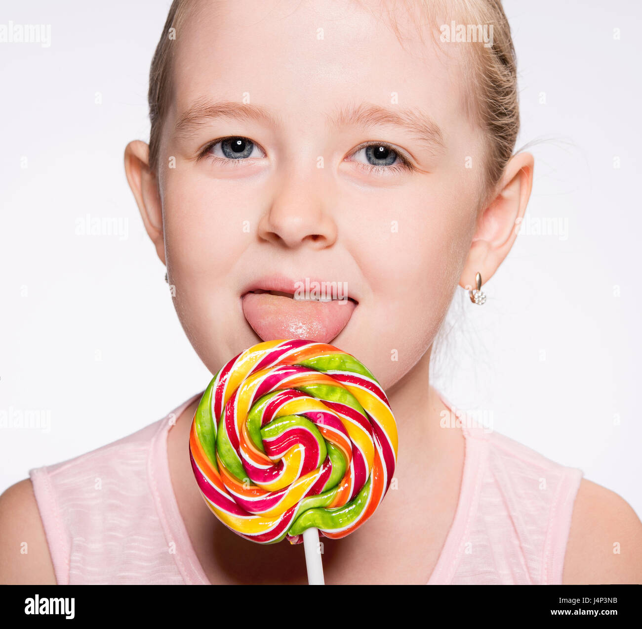 young girl licks a bright icicle on a stick Stock Photo
